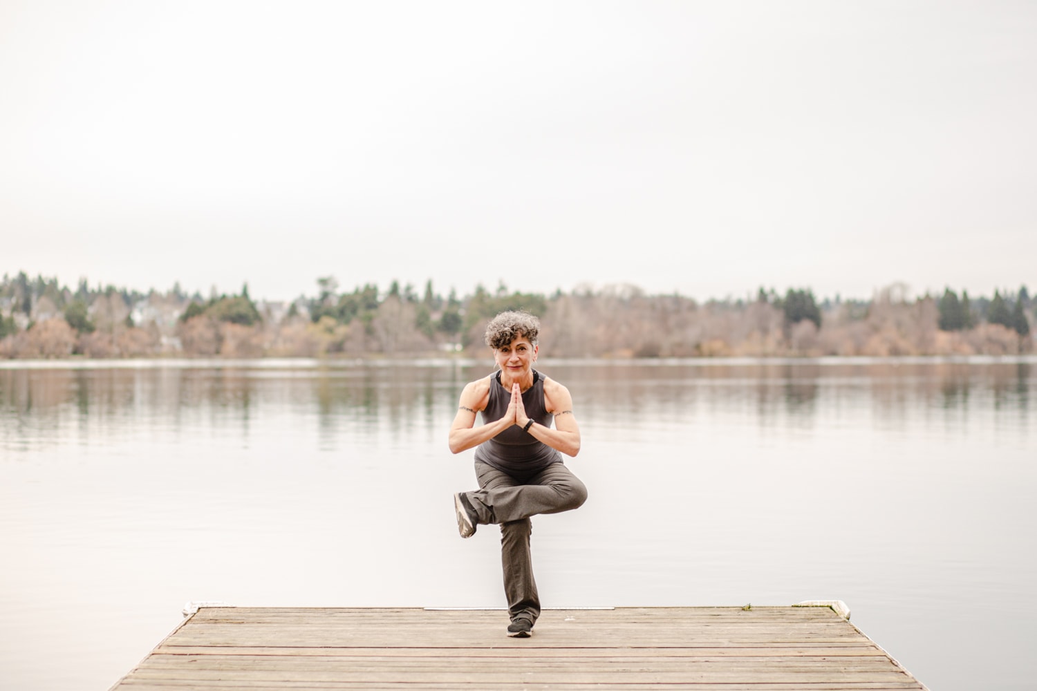 Chiara in a yoga pose on a dock by the lake